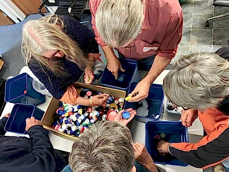 A group of older people sort through a box of plastic pieces to recycle