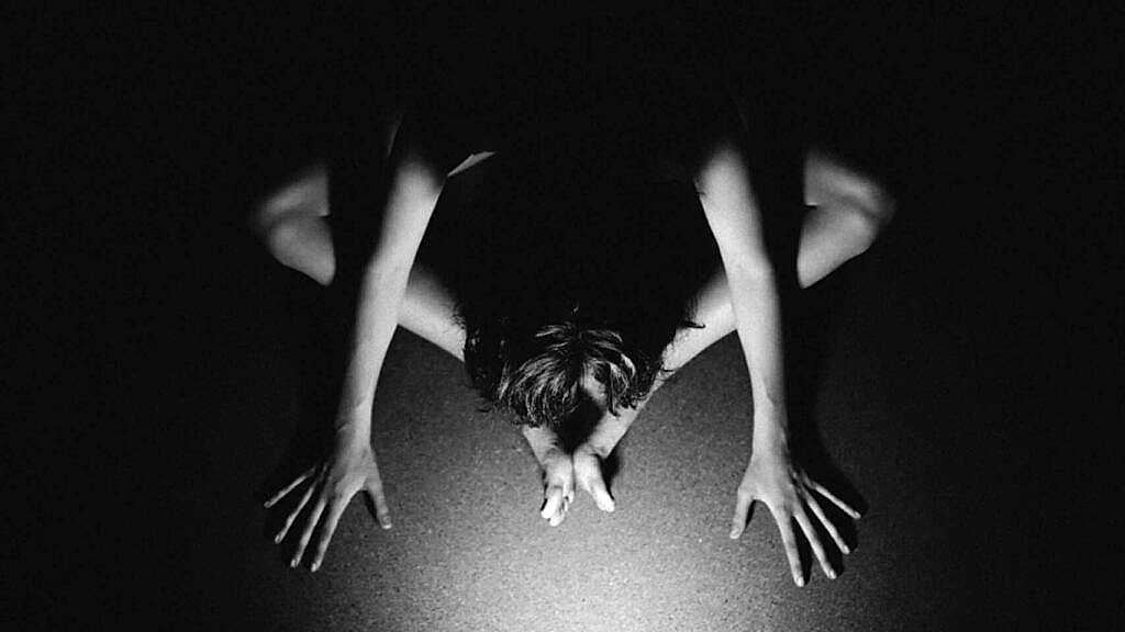 a black and white photo of a person cross legged taken from above.