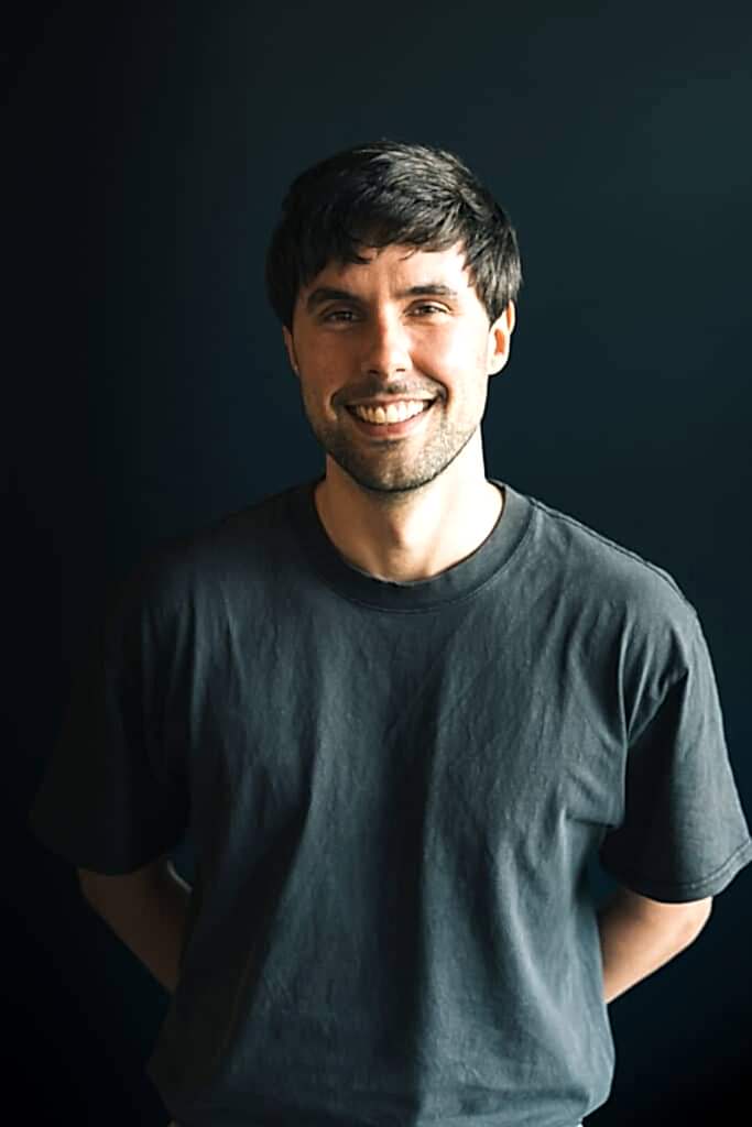 a man in a black t shirt smiles at the camera