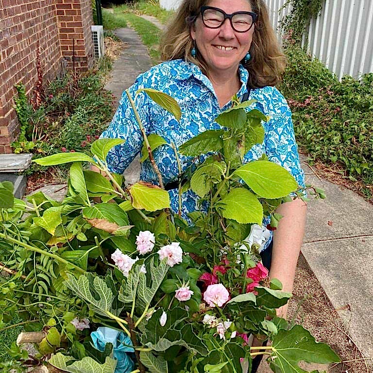 a woman smiles with a collection of plants