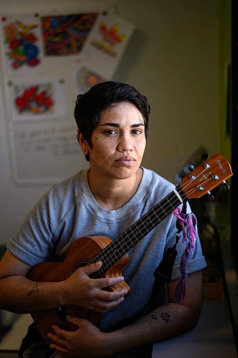 A woman holding a guitar looks at the camera